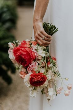 a woman holding a bouquet of flowers in her hand and wearing a wedding ring on her finger