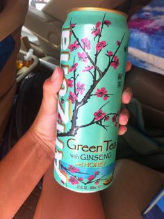 a woman holding up a can of green tea with ginsen's almonds