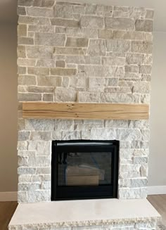 a stone fireplace with a wood mantel in the middle and white brick on top