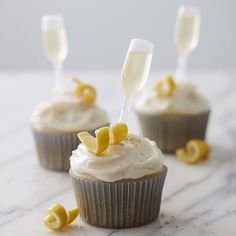 three cupcakes with frosting and lemon wedges on the top one is filled with champagne