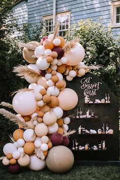 balloons and feathers are hanging from the side of a sign in front of a house