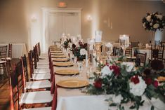 the tables are set with white and red flowers, candles, and place settings for dinner