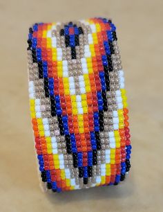 Artist: Navajo Beadwork artist Zane Johnson Medium: Size #12 glass seed beads backed with leather on metal bracelet shank Size: 2 3/4" Across with a 1 1/2" Opening x 1 1/4" H Can have a little play in size of larger or smaller Beautiful and traditional Fire Colors pattern Gender friendly! Southwestern Style Multicolor Beaded Bracelets With Large Beads, Southwestern Multicolor Beaded Bracelet With Spacer Beads, Multicolor Southwestern Beaded Bracelet, Navajo Beadwork, Indian Beadwork, Metal Bracelet, Indian Summer, Glass Seed Beads, Native American Art