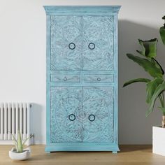 a blue cabinet sitting on top of a wooden table next to a potted plant