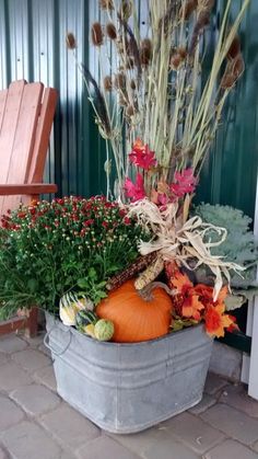 a bucket filled with lots of different types of flowers and plants next to a chair