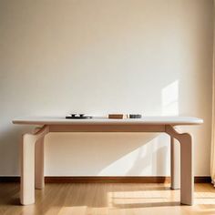 a white table sitting in front of a window next to a wooden floor and wall