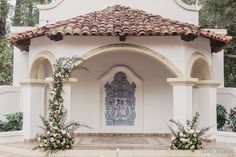 an outdoor wedding venue with flowers and greenery on the front entrance to the building