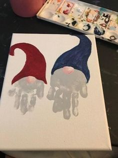 two gnomes painted on canvases next to a paintbrush