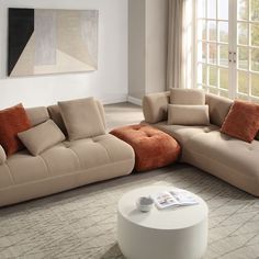 a living room with a large sectional couch and coffee table in front of a window