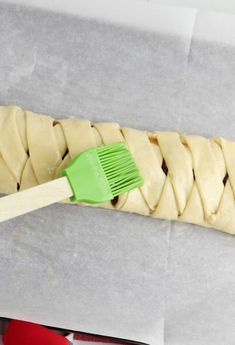 a long piece of bread with a green brush on it sitting on top of wax paper