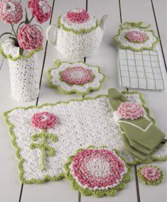 crocheted table cloths, cups and vases with pink flowers on them