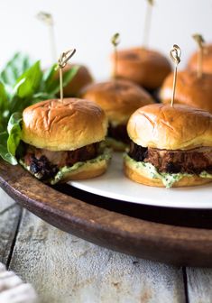 small sandwiches with toothpicks on them sit on a plate next to some lettuce