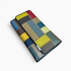 two wallets sitting next to each other on top of a white surface and one has a multicolored patchwork pattern