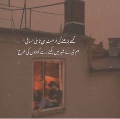 a person sitting on a window sill in front of a building with the words written in arabic