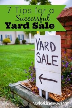 a yard sale sign sitting on top of a cement block in front of a house