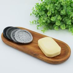 three pieces of soap sitting on top of a wooden tray next to a green plant