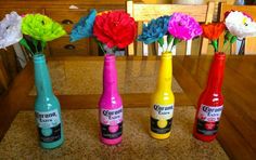 four colorful bottles with flowers in them sitting on a counter top next to each other