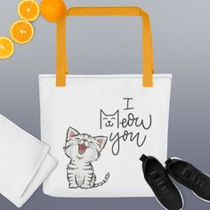 a white bag with an image of a cat on it and some oranges next to it