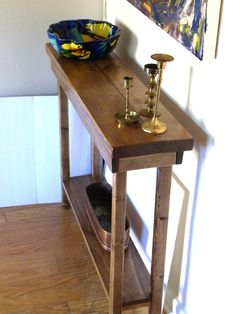 a wooden table with two candles on it and a bowl sitting on top of it