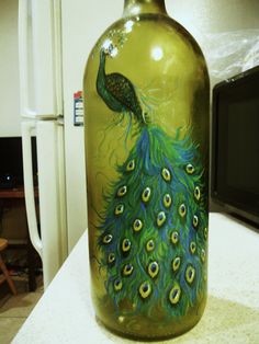 a green glass bottle with a peacock painted on it's side sitting on a counter next to a microwave