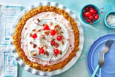 a pie with whipped cream, cherries and nuts sits on a plate next to other plates