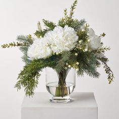 a vase with white flowers and greenery in it