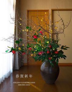 a vase filled with lots of flowers on top of a wooden floor next to a window