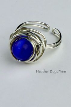 a silver ring with a blue stone in it's center on a white surface