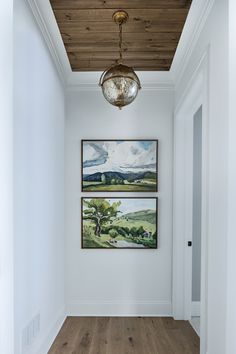 two paintings hang on the wall in an empty hallway