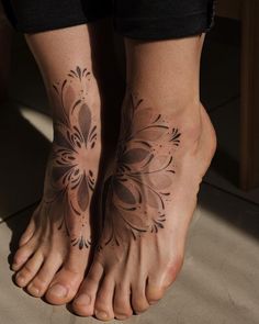 two feet with tattoos on them and one has a flower design on the bottom of it