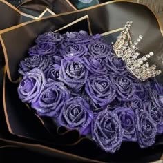 a bouquet of purple roses with a tiara on top