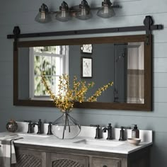 a bathroom vanity with two sinks and a large mirror over the sink that hangs above it