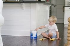 a little boy sitting on the floor playing with a can of water and toothbrushes