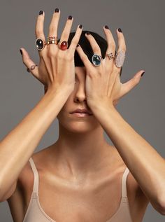 a woman holding her hands up to her face with two rings on it's fingers