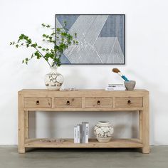 a wooden table with two drawers and some books on it next to a potted plant