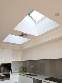 an empty kitchen with skylights and white cabinets