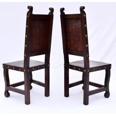 two wooden chairs sitting side by side in front of a white background, one with studded straps and the other without