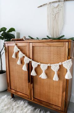 a crocheted tasselled curtain hanging on a cabinet in a living room