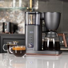 a coffee maker sitting on top of a kitchen counter next to a cup of coffee