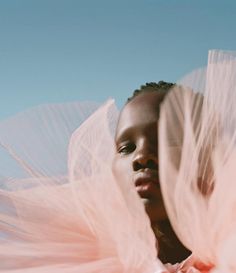 a woman with pink tulle on her head and dress in front of blue sky