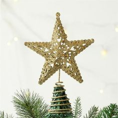 a gold star ornament hanging from a christmas tree