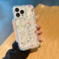 a woman holding up her phone case with flowers on the front and back cover in clear