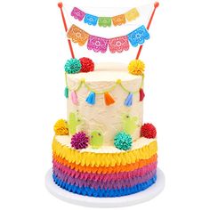 a multi - colored cake decorated with pom poms and streamers on top