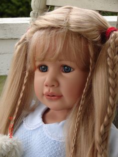 a doll with long blonde hair and blue eyes sitting on a porch chair next to a teddy bear