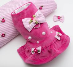 a pair of pink shoes with bows and pearls on the bottom are laying next to two pillows