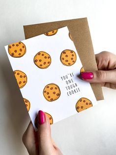 a woman holding up a card with chocolate chip cookies on it