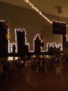 a room filled with tables and chairs covered in white string lights that spell out the word happy new year