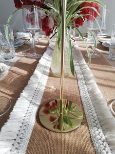 there is a vase with flowers in it on the dining room table set for dinner