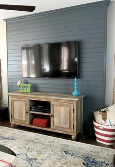 a flat screen tv mounted to the side of a wooden cabinet in a living room