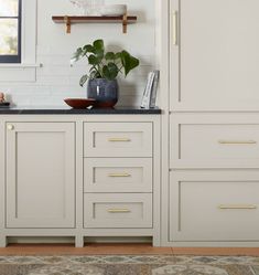 a kitchen with white cabinets and black counter tops, along with a rug on the floor